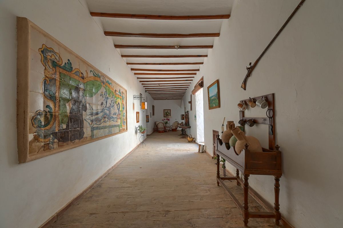 Couloir historique avec poutres en bois apparentes, sol en pierre naturelle et une grande fresque murale en azulejos peints à la main.