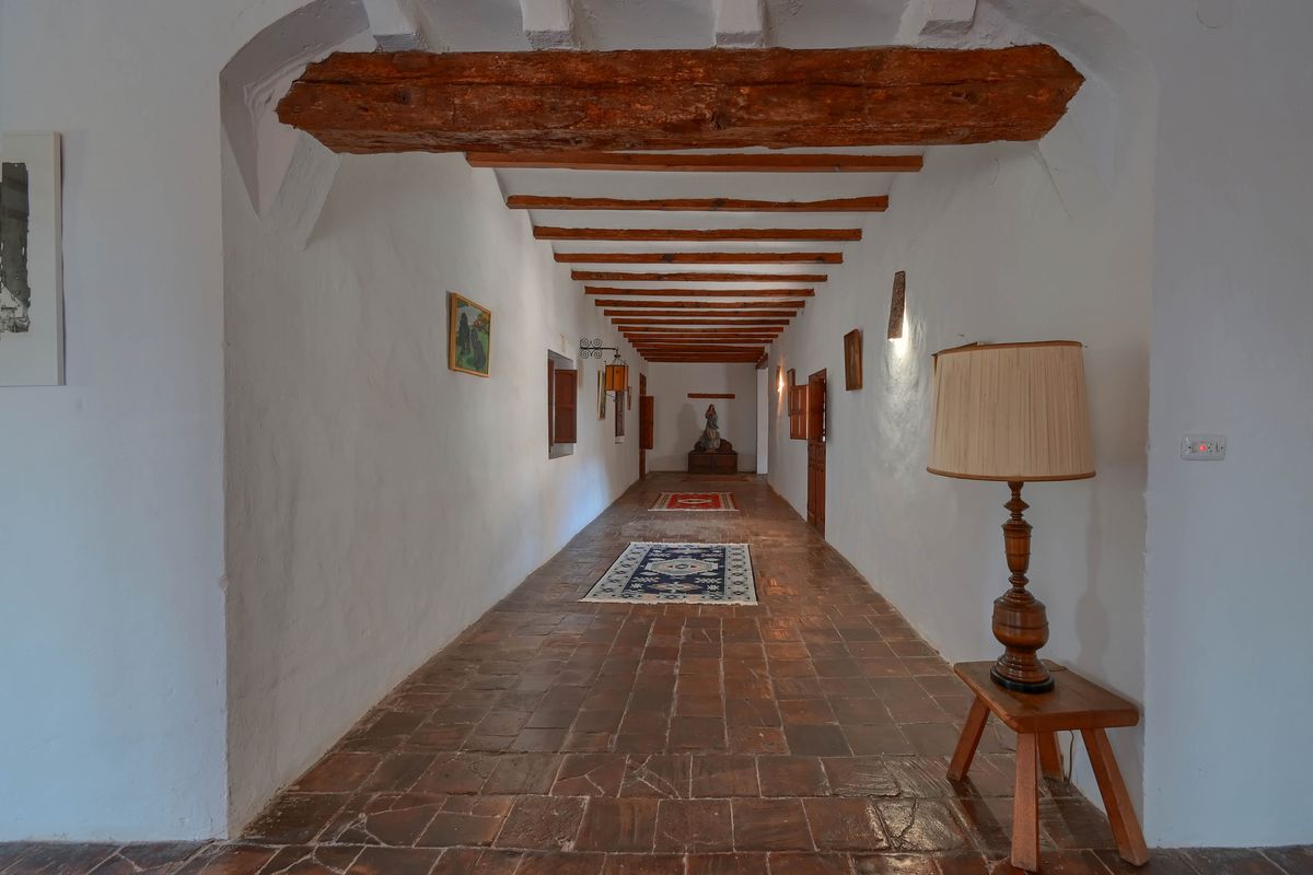 Couloir traditionnel doté de sols en terre cuite, de murs blanchis à la chaux et d'un plafond avec des poutres en bois massif apparentes.