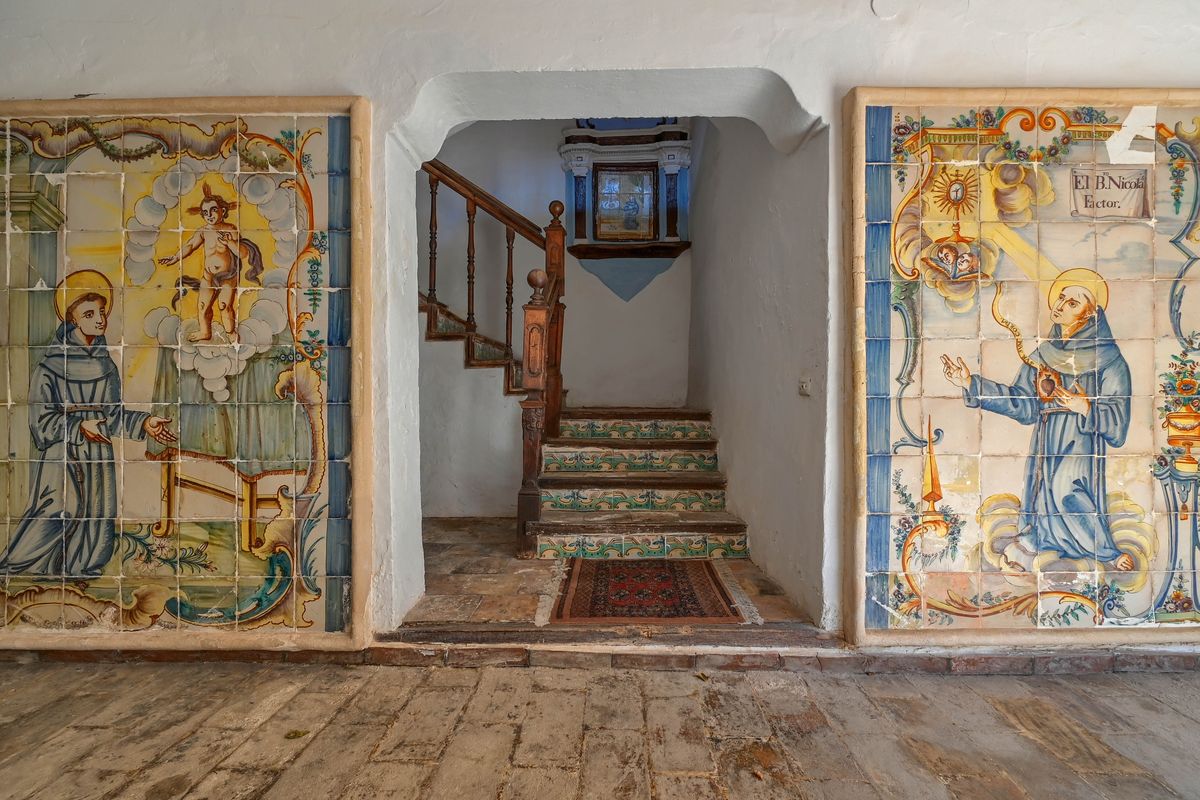 Hall d'entrée orné de fresques historiques en azulejos, murs épais à la chaux et escalier avec contremarches en céramique décorée et rampe en bois.