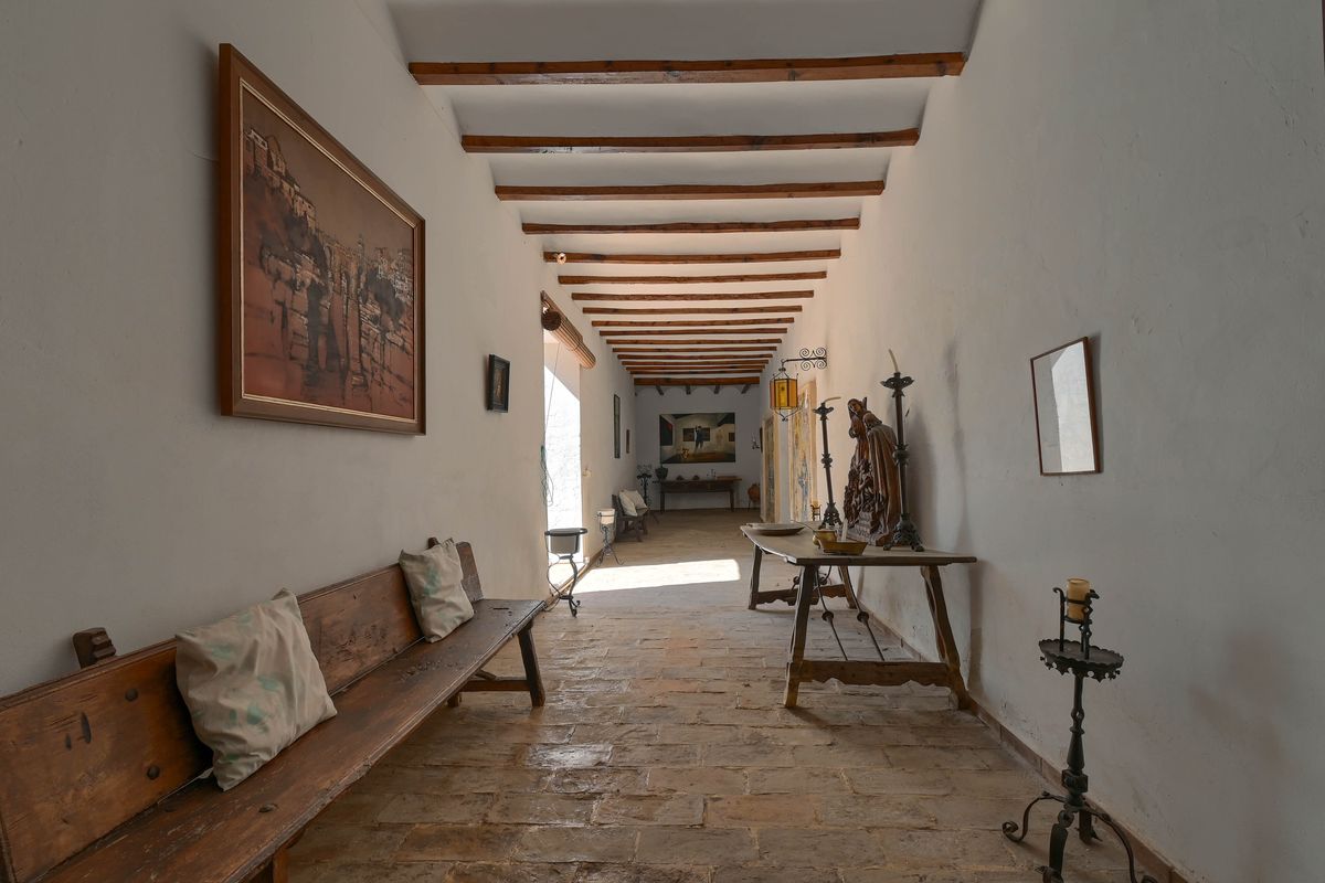 Long couloir de caractère avec poutres en bois d'origine, sol en terre cuite et mobilier rustique sous un plafond traditionnel.