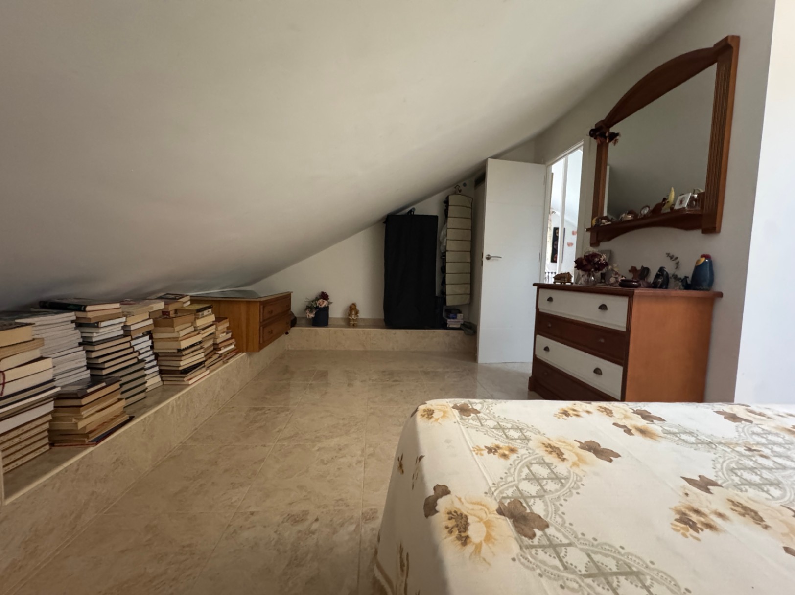 Chambre mansardée avec bibliothèque intégrée et commode en bois.