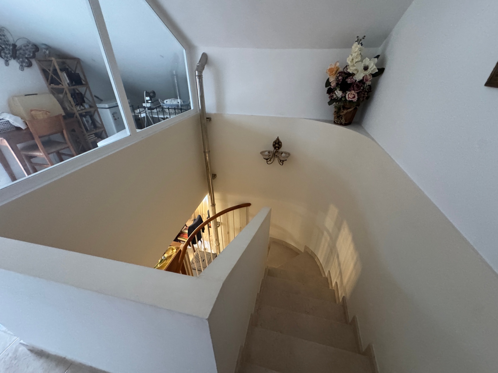 Détail de l'escalier intérieur avec rampe en bois et marches en pierre.