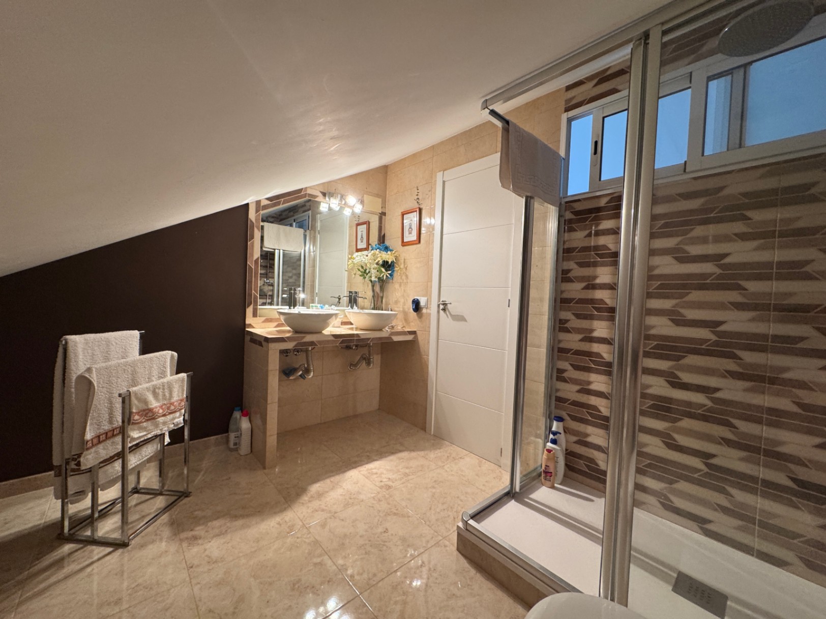 Salle de bain avec double vasque et douche avec paroi de verre coulissante.