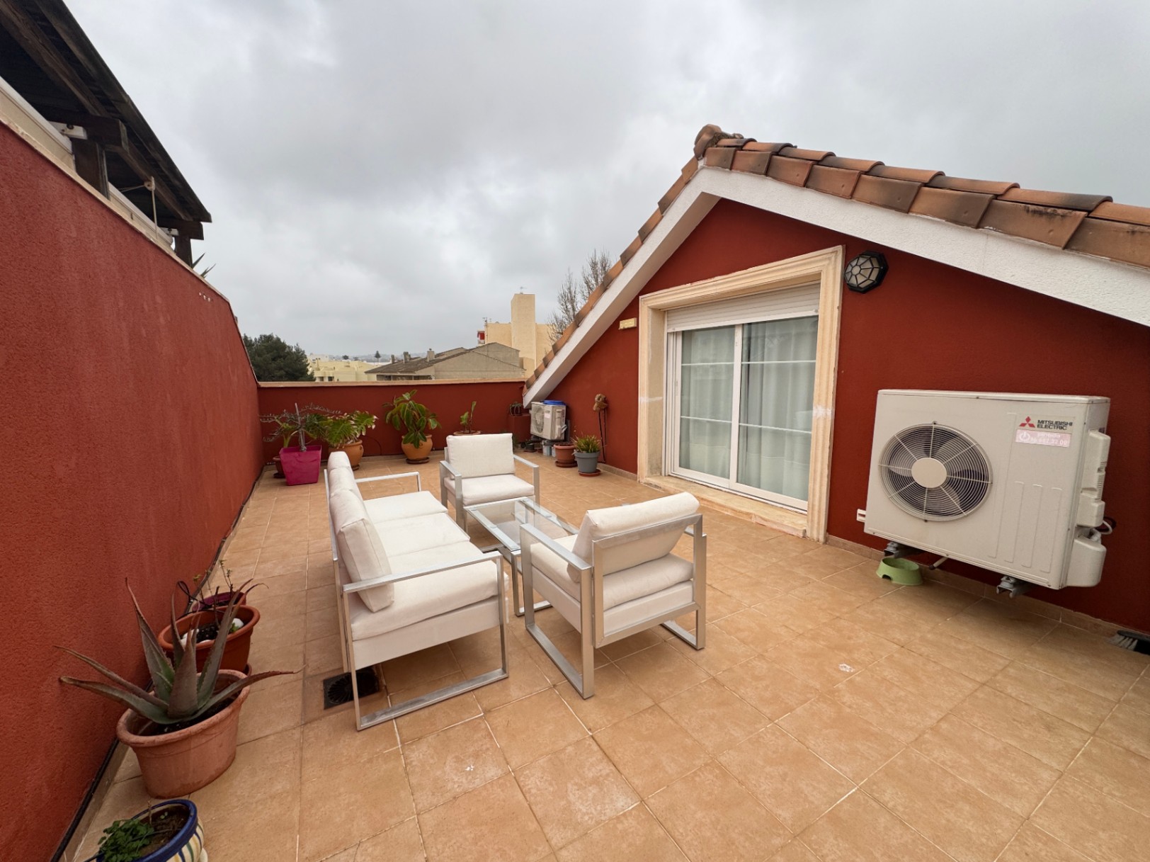 Terrasse carrelée avec murs rouges et mobilier d'extérieur blanc.