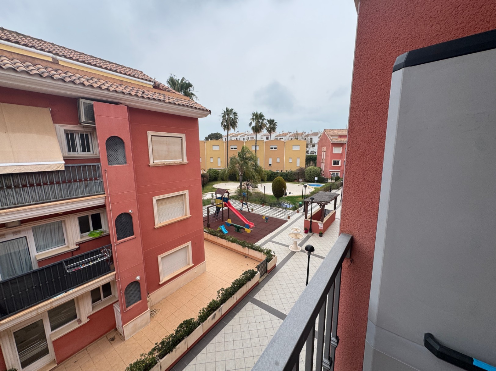 Vue du balcon donnant sur la cour intérieure avec aire de jeux.