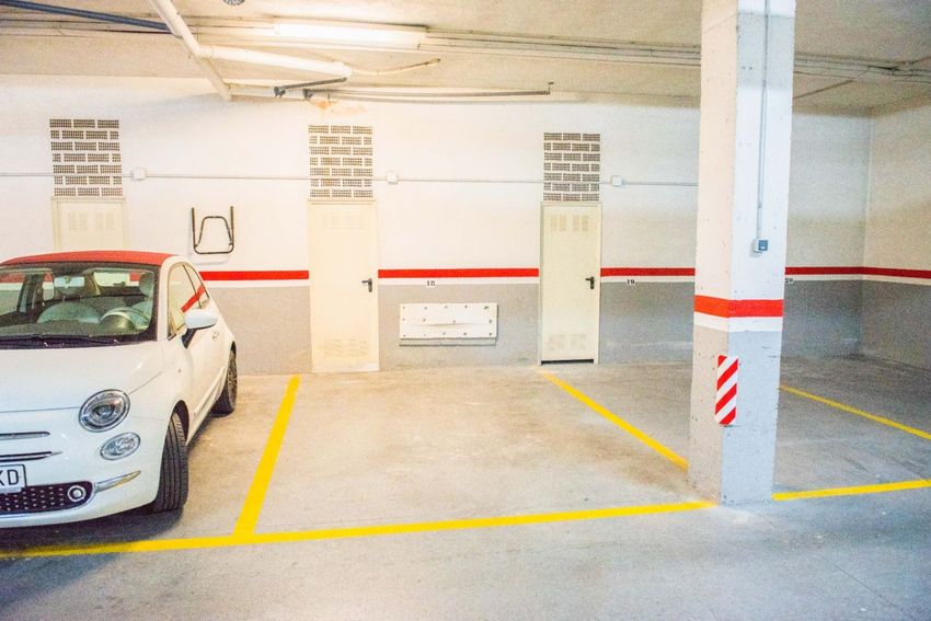 Place de parking souterrain spacieuse avec marquages jaunes clairs sur sol en béton. Comprend un éclairage aérien, des piliers et des unités de rangement. Place de parking souterrain spacieuse avec marquages jaunes clairs sur sol en béton. Comprend un éclairage aérien, des piliers et des unités de rangement.