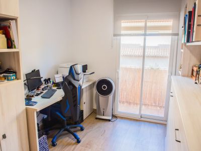 Bureau fonctionnel avec un grand bureau, une chaise ergonomique et des étagères en bois clair. Des portes coulissantes mènent à un espace extérieur baigné de lumière naturelle.