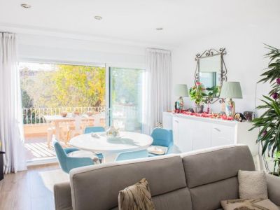 Espace salon-salle à manger lumineux offrant un accès direct à une terrasse privée avec mobilier extérieur. Les portes coulissantes vitrées apportent lumière naturelle et vue sur les arbres.