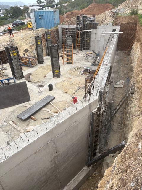 Phase de fondation présentant des murs de soutènement en béton armé et des coffrages verticaux pour les colonnes structurelles du bâtiment.
