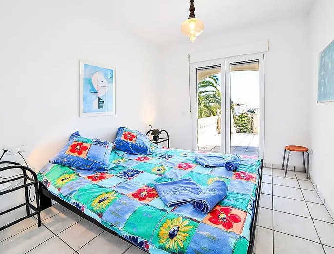 Chambre lumineuse avec carrelage blanc et accès direct à une terrasse offrant une vue sur la végétation méditerranéenne et une clarté optimale.