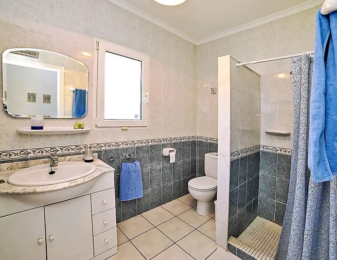 Salle de bain fonctionnelle avec carrelage bicolore, plan de toilette en marbre et douche à l'italienne. Une fenêtre assure lumière naturelle et aération optimale.