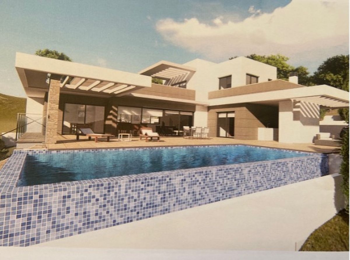 Extérieur de villa moderne avec piscine à débordement en mosaïque bleue, vaste terrasse ensoleillée et architecture contemporaine aux accents de pierre.