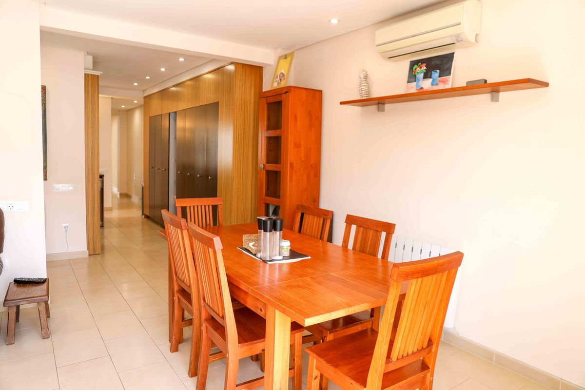 Espace salle à manger avec table en bois, vitrine assortie et vue sur un couloir dégagé doté de rangements intégrés et d'un éclairage encastré.