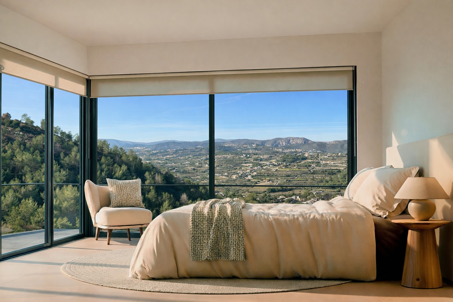Chambre avec baies vitrées d'angle offrant une vue panoramique sur la vallée et les montagnes. Tons neutres, table de chevet en bois et lumière naturelle.