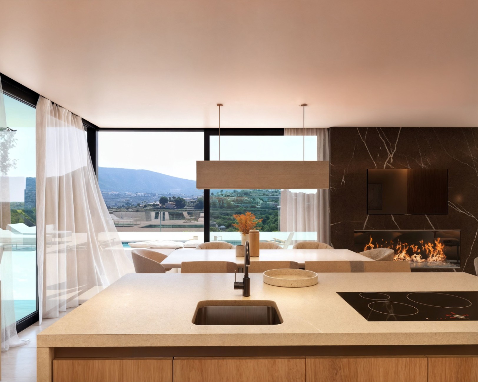 Cuisine ouverte avec îlot en pierre, espace salle à manger et salon doté d'une cheminée sur mur en marbre sombre, offrant une vue dégagée sur les montagnes.