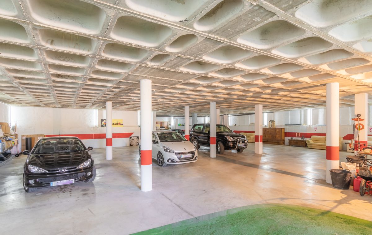 Spacieux garage souterrain doté d'un plafond en caissons de béton, de colonnes de soutien blanches avec marquages rouges et d'un vaste espace pour plusieurs véhicules.