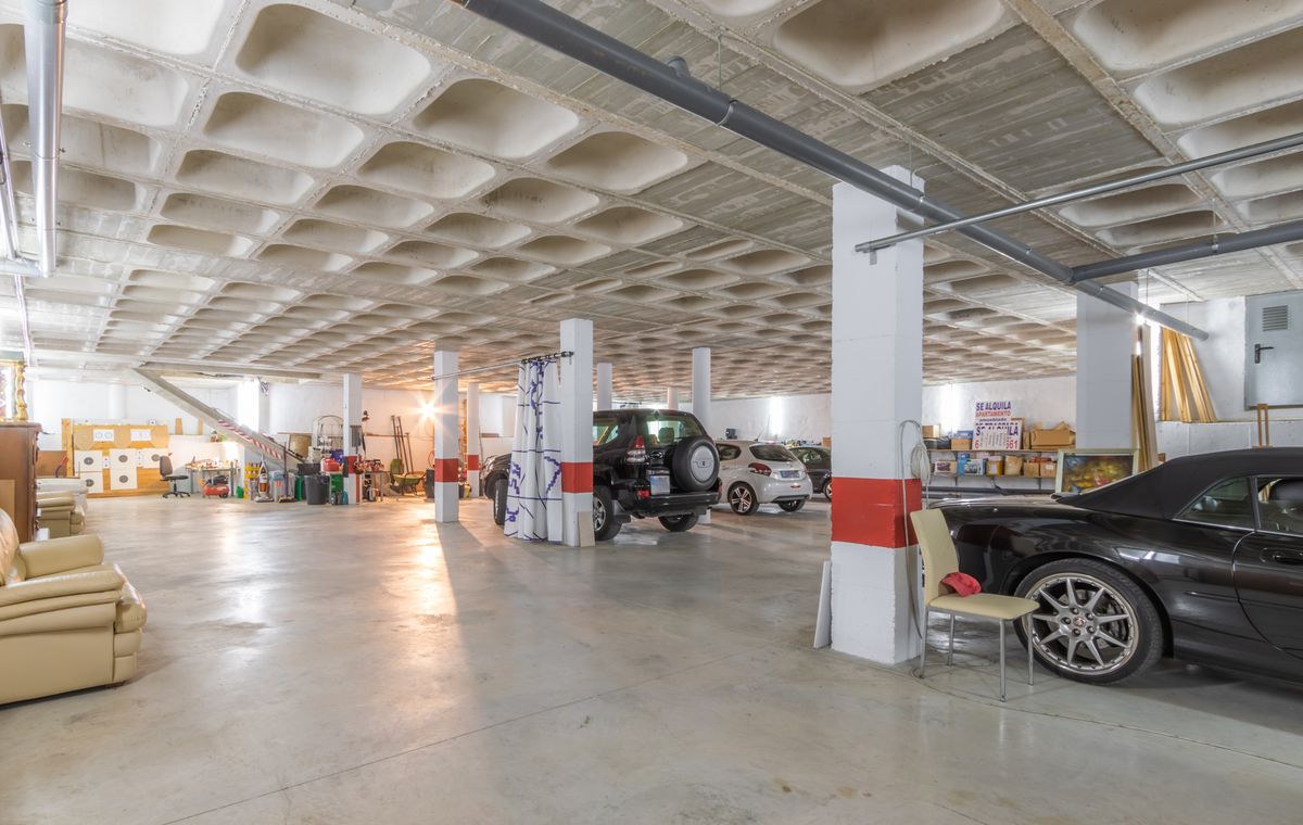 Vaste garage souterrain avec plafond à caissons en béton, piliers de soutien marqués de rouge et espace généreux pour plusieurs véhicules et stockage.