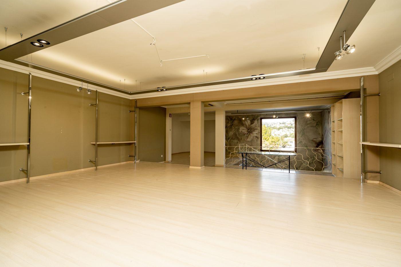 Espace commercial ouvert avec sol en stratifié clair, étagères métalliques modulables et une fresque florale à côté d'une fenêtre offrant une vue dégagée.