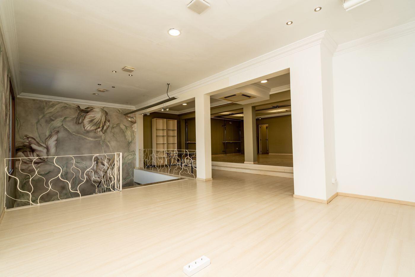 Niveau mezzanine spacieux avec parquet clair, éclairage encastré et garde-corps métallique ondulé. Une grande fresque florale orne le mur latéral.