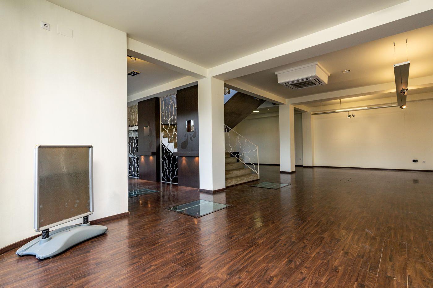 Vaste espace ouvert avec parquet sombre, dalles de sol vitrées et cloisons décoratives. Équipé d'une climatisation centrale et d'un escalier avec rampe métallique blanche.