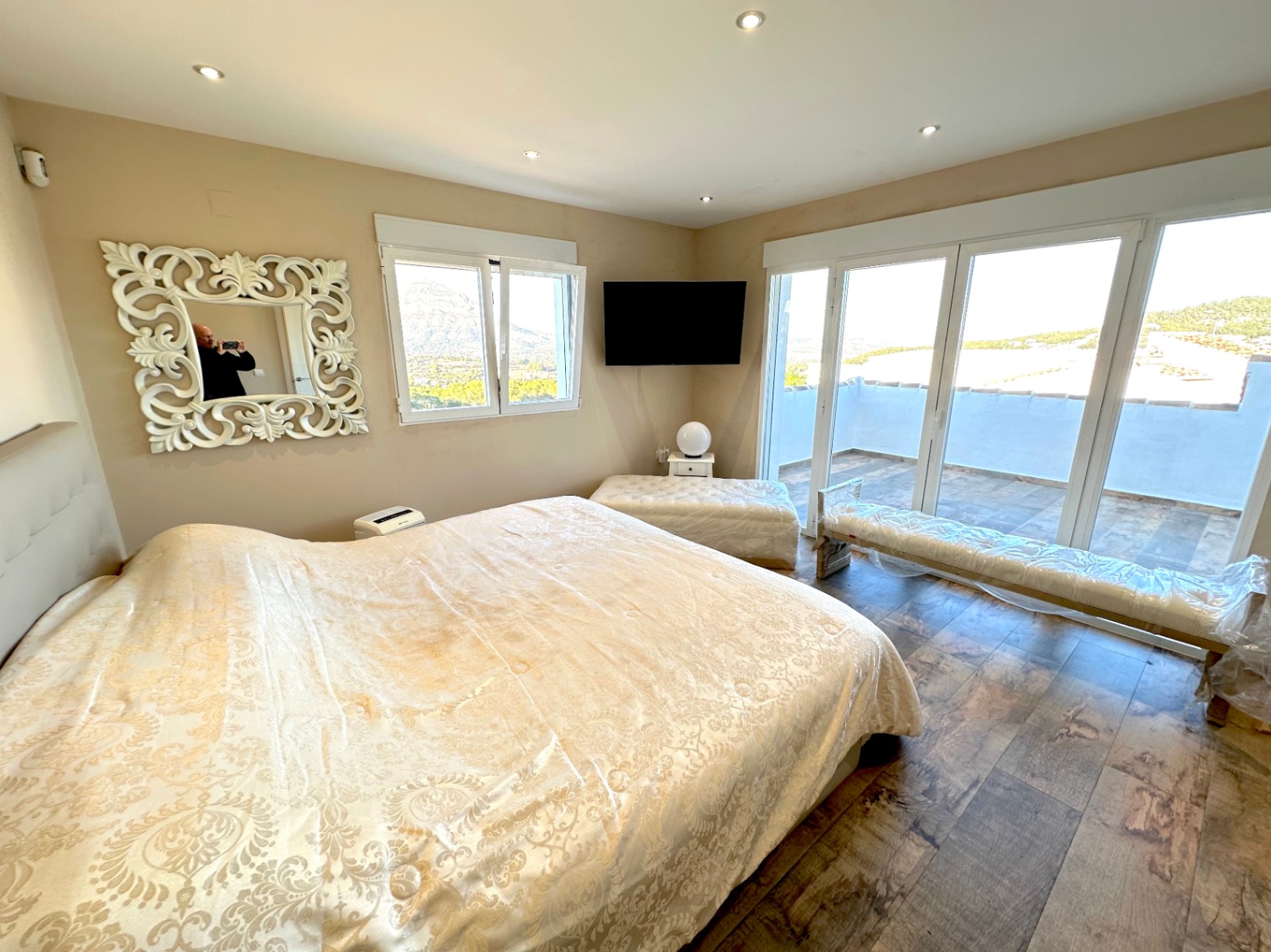 Chambre principale avec sol effet bois, accès terrasse privée et vue sur le Montgó. Comprend un éclairage encastré et de grandes baies vitrées.