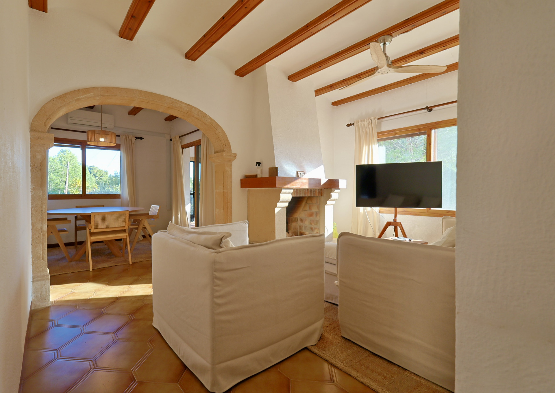 Salon avec poutres apparentes, arche en pierre naturelle et sol en terre cuite. Comprend une cheminée traditionnelle et une vue sur la salle à manger.