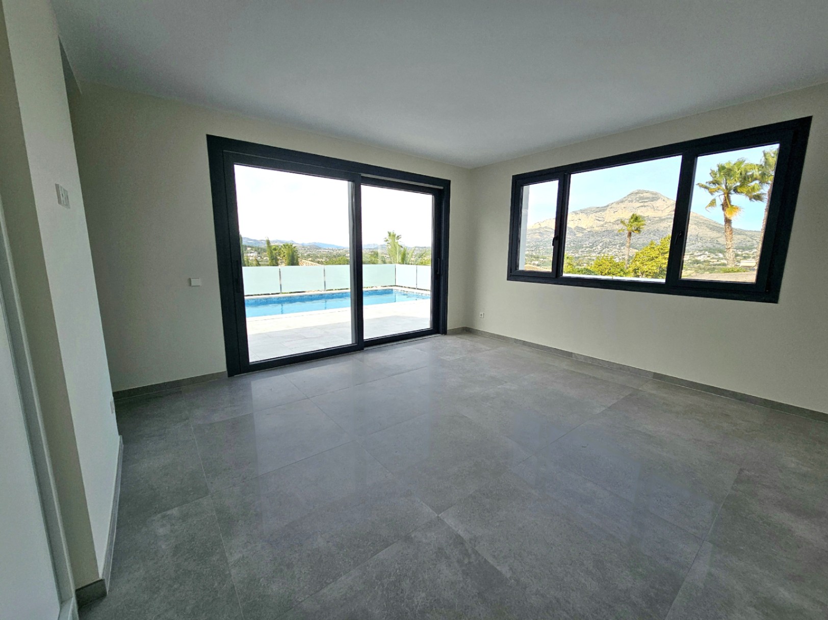 Pièce lumineuse avec carrelage, vue sur la piscine et le Montgó.