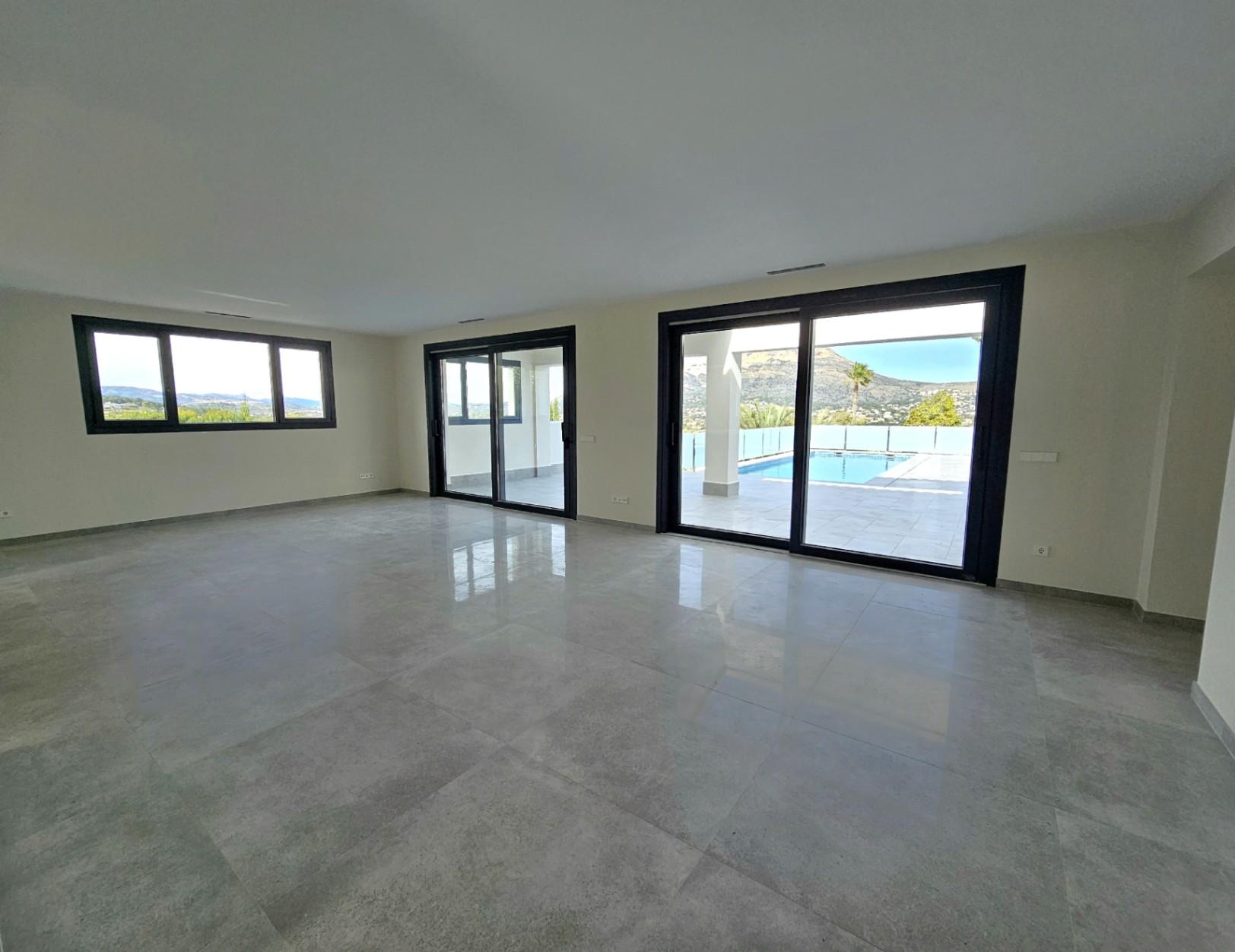 Salon spacieux avec carrelage et accès à la terrasse avec piscine et vue sur le Montgó.