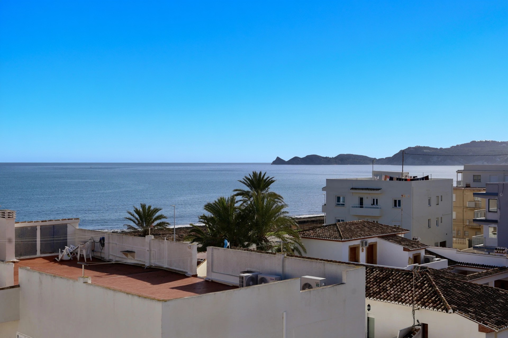 Vue surélevée depuis la propriété sur les toits blancs et les palmiers, s'étendant vers la mer Méditerranée et le cap à l'horizon.