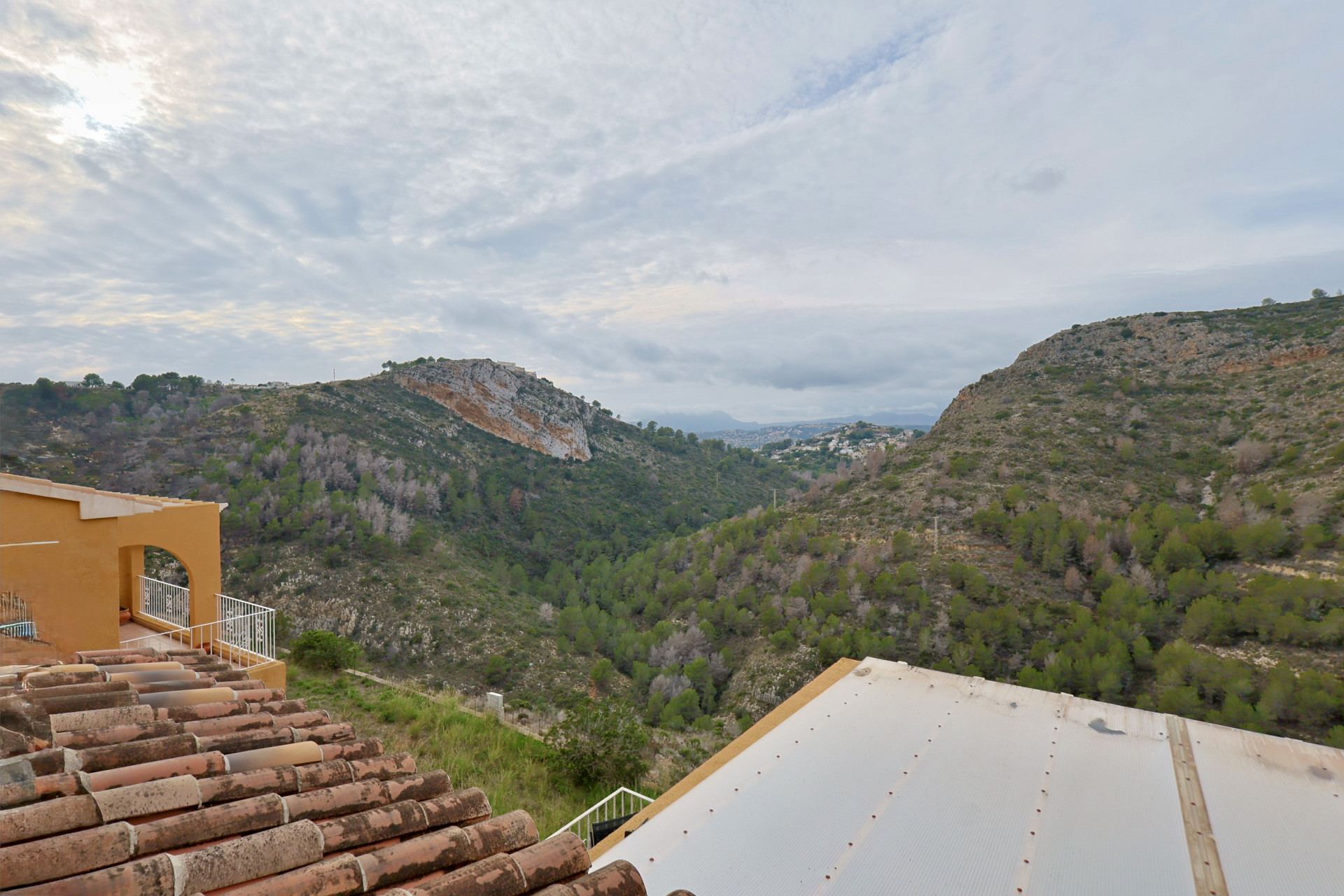 Vue panoramique sur la vallée et les collines environnantes, mettant en valeur les toits en tuiles traditionnelles et les détails architecturaux.