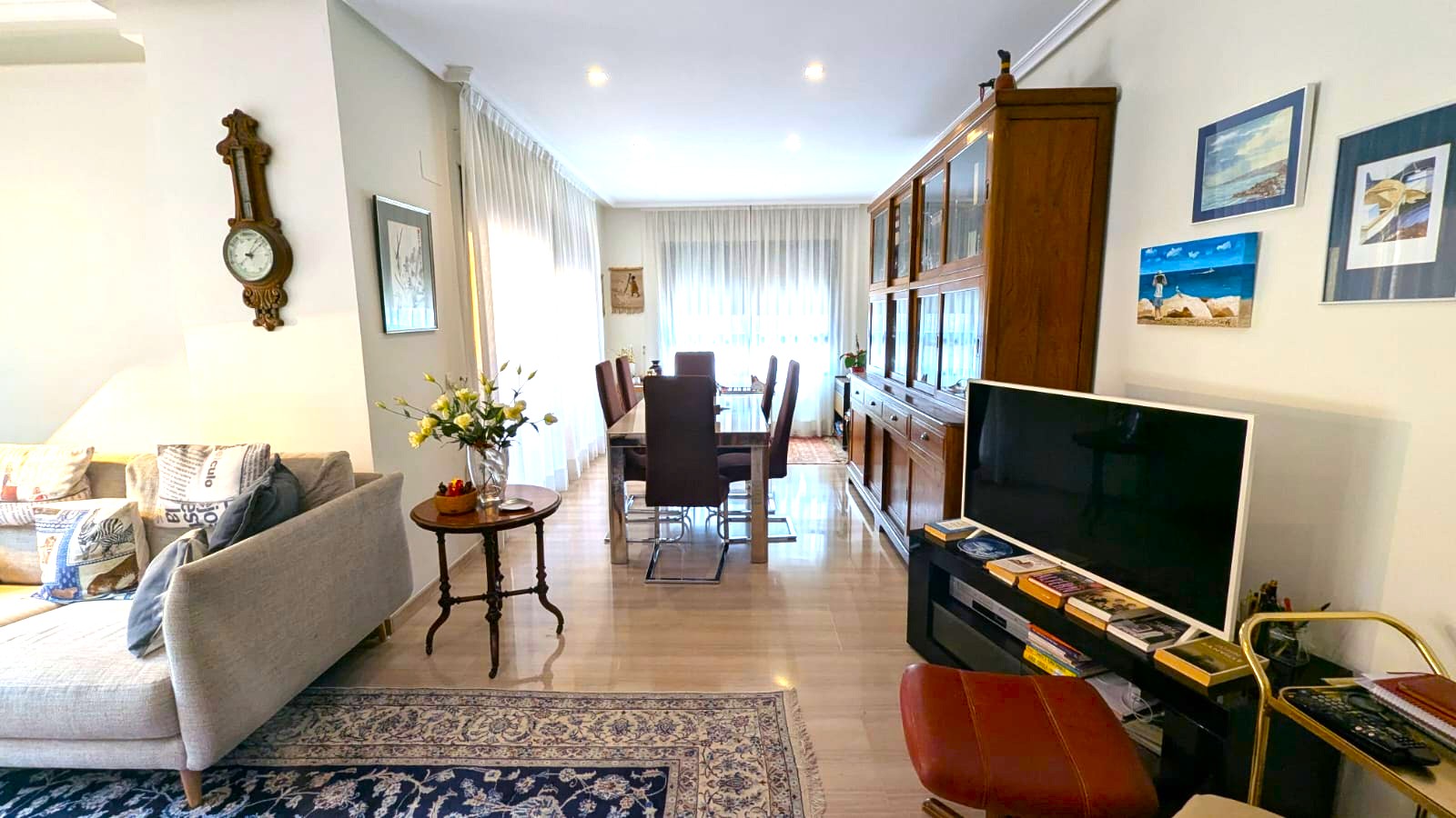 Espace salon-salle à manger spacieux avec sol en marbre poli, grand buffet en bois classique et table à manger en verre sous des spots encastrés.