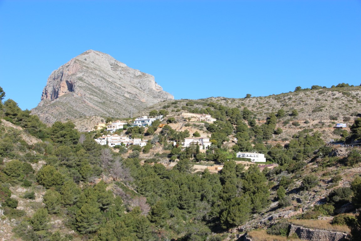 Vue sur les villas à flanc de colline avec le Montgó en arrière-plan sous un ciel bleu.