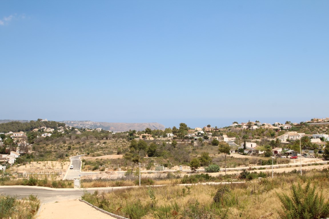 Vue panoramique du lotissement avec maisons dispersées et végétation indigène, sous un ciel bleu dégagé.