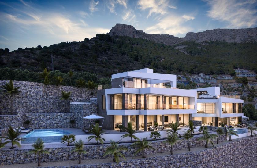 Vue extérieure de la villa avec piscine à débordement et façade en pierre naturelle.