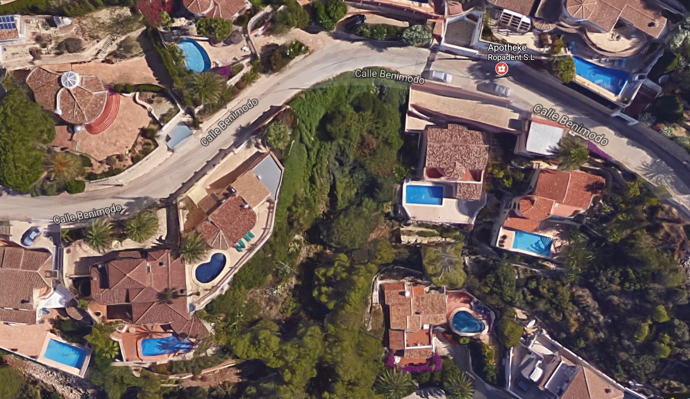 Vue aérienne d'une parcelle à Benimeit, Moraira, entourée de villas avec piscines et verdure.
