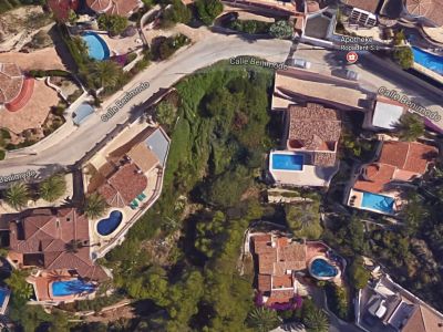 Vue aérienne d'une parcelle à Benimeit, Moraira, entourée de villas avec piscines et verdure.
