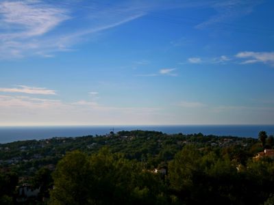 Vue panoramique de Benimeit, Moraira, avec la mer Méditerranée en arrière-plan et un ciel bleu nuageux.