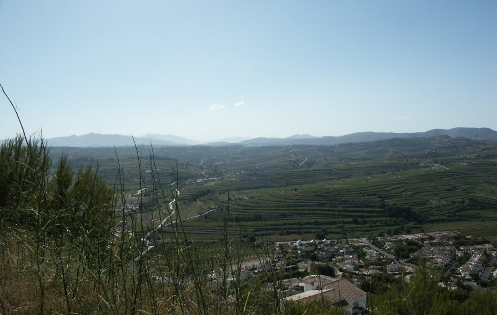 Vue panoramique de Benitachell avec des terrasses agricoles et des montagnes au loin.