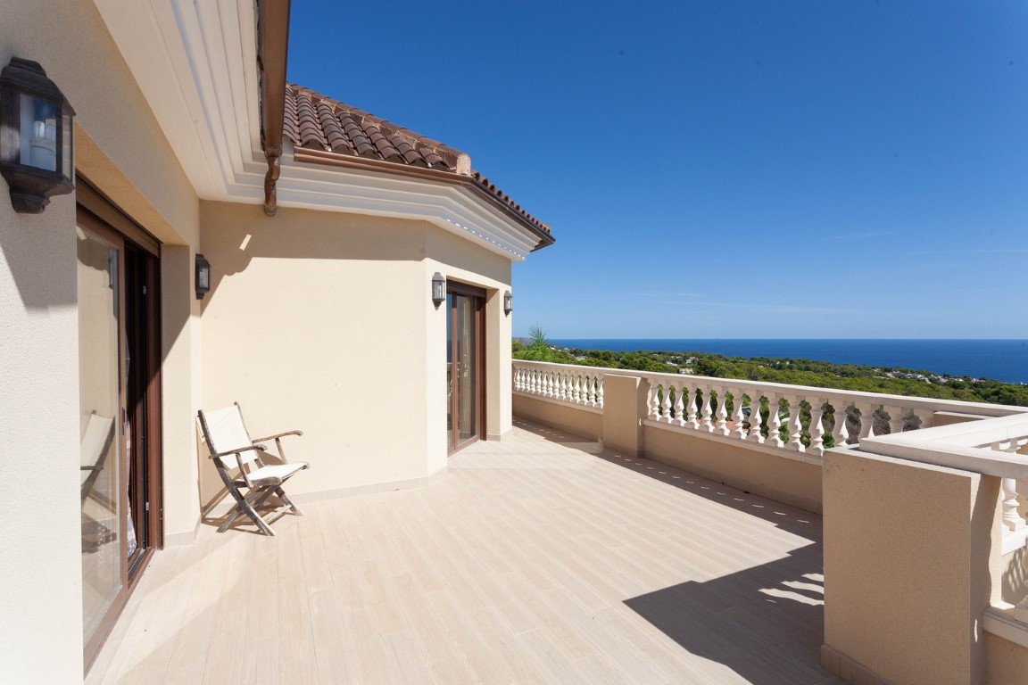 Grand balcon à l'étage avec balustrade classique, carrelage clair et vue panoramique sur la mer Méditerranée et la campagne environnante.