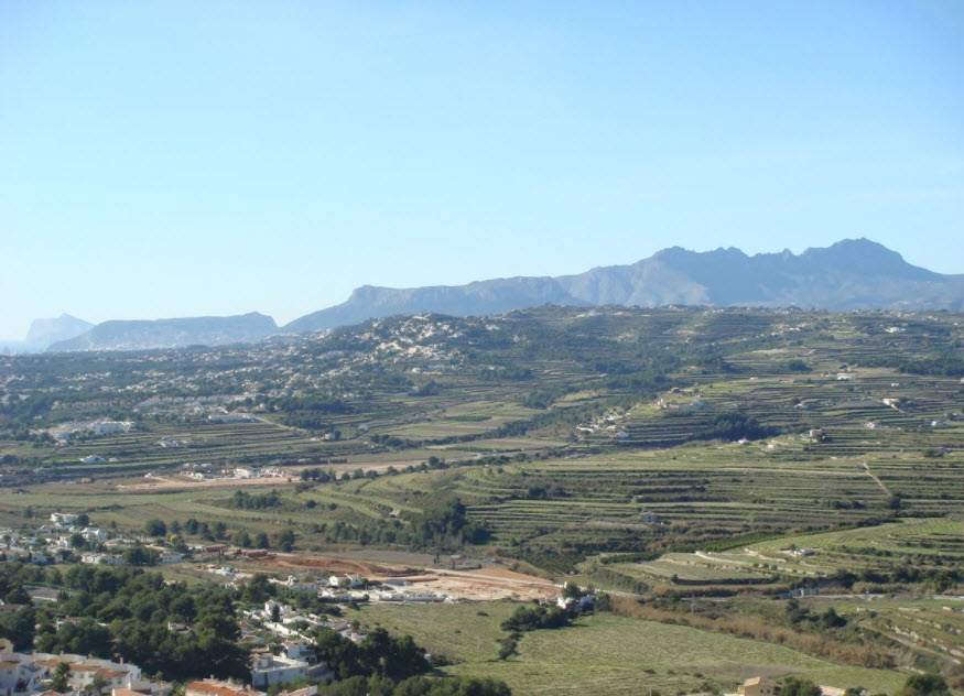 Vue panoramique sur les terrasses agricoles et les reliefs montagneux de Benitachell, illustrant l'environnement naturel et dégagé du site.