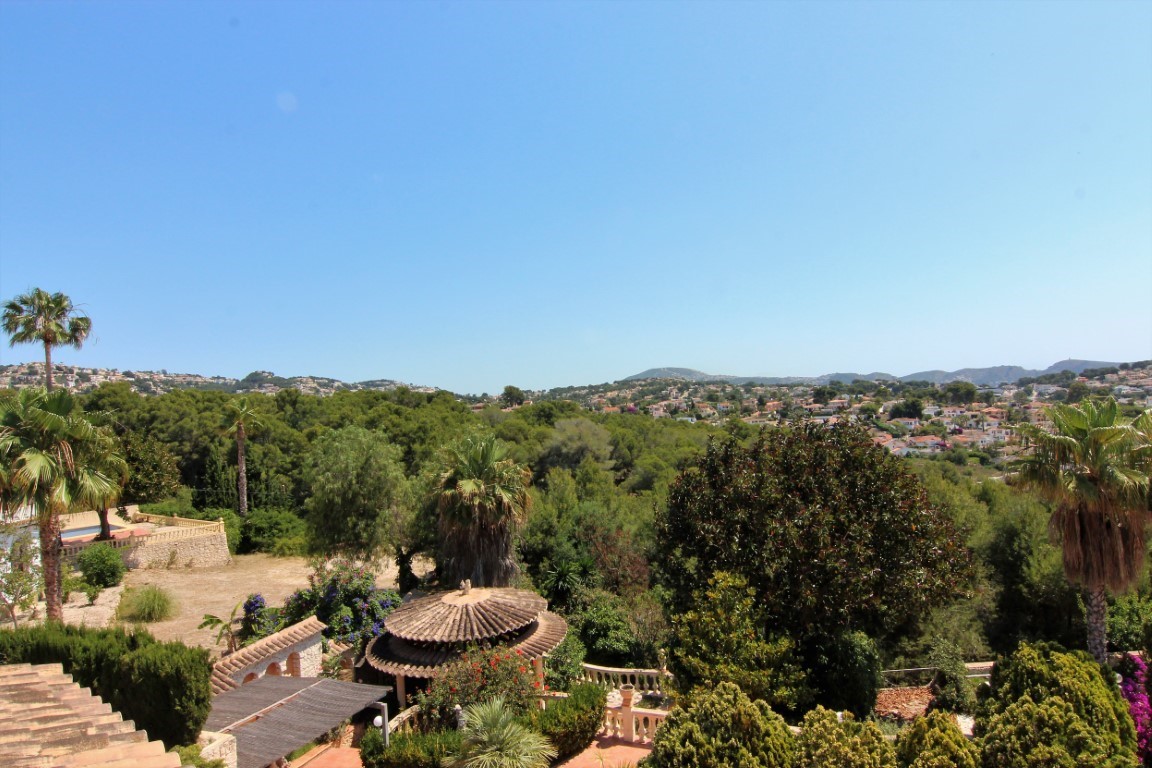 Vue panoramique depuis la terrasse supérieure sur le jardin méditerranéen avec palmiers, un gazebo circulaire aux tuiles étagées et les collines résidentielles.