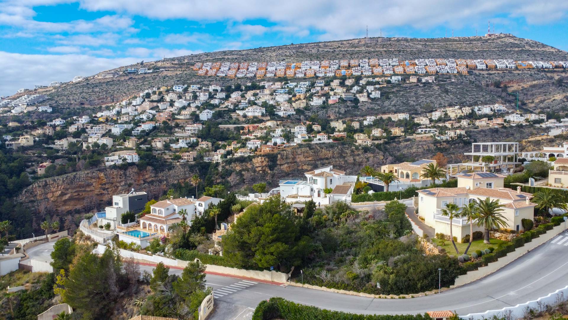 Vue aérienne panoramique du quartier résidentiel de Cumbre del Sol, illustrant l'implantation des villas sur la colline au milieu de la végétation méditerranéenne.