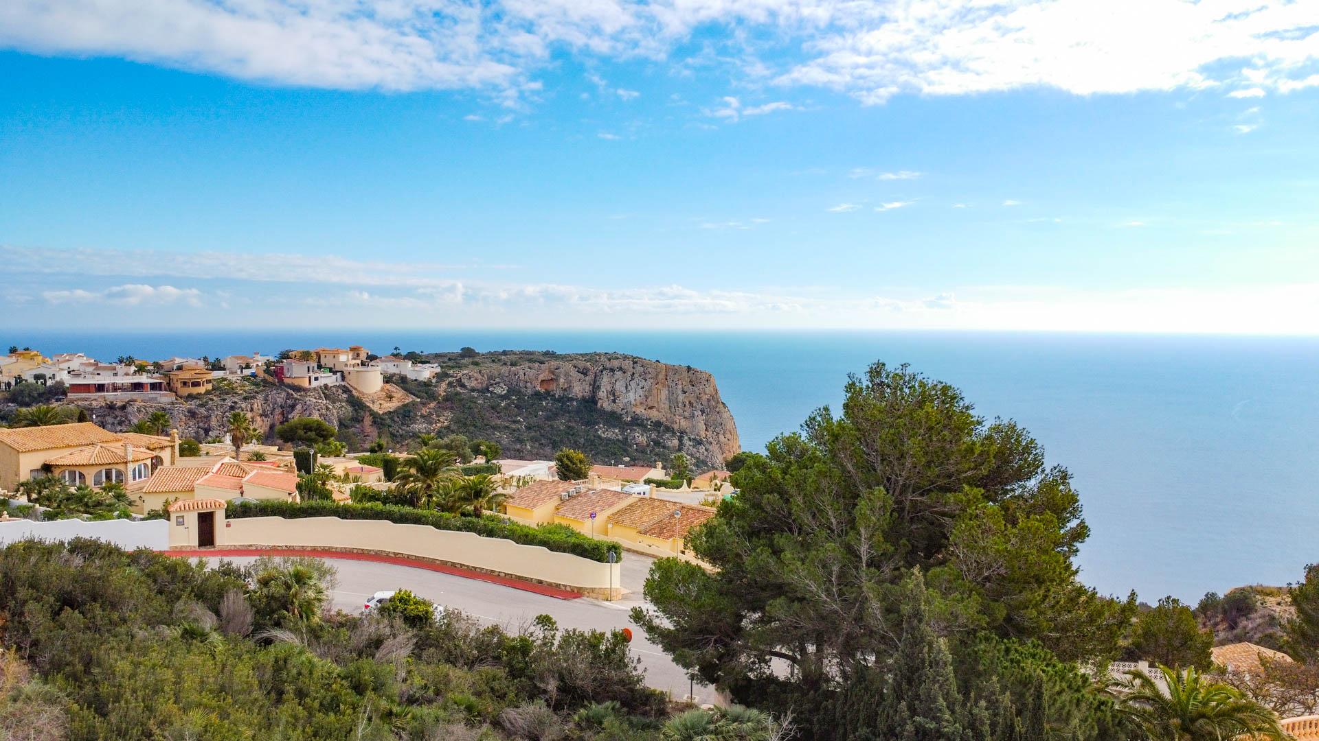 Vue panoramique depuis Cumbre del Sol illustrant le littoral méditerranéen, les falaises escarpées et les villas résidentielles dans un paysage verdoyant.