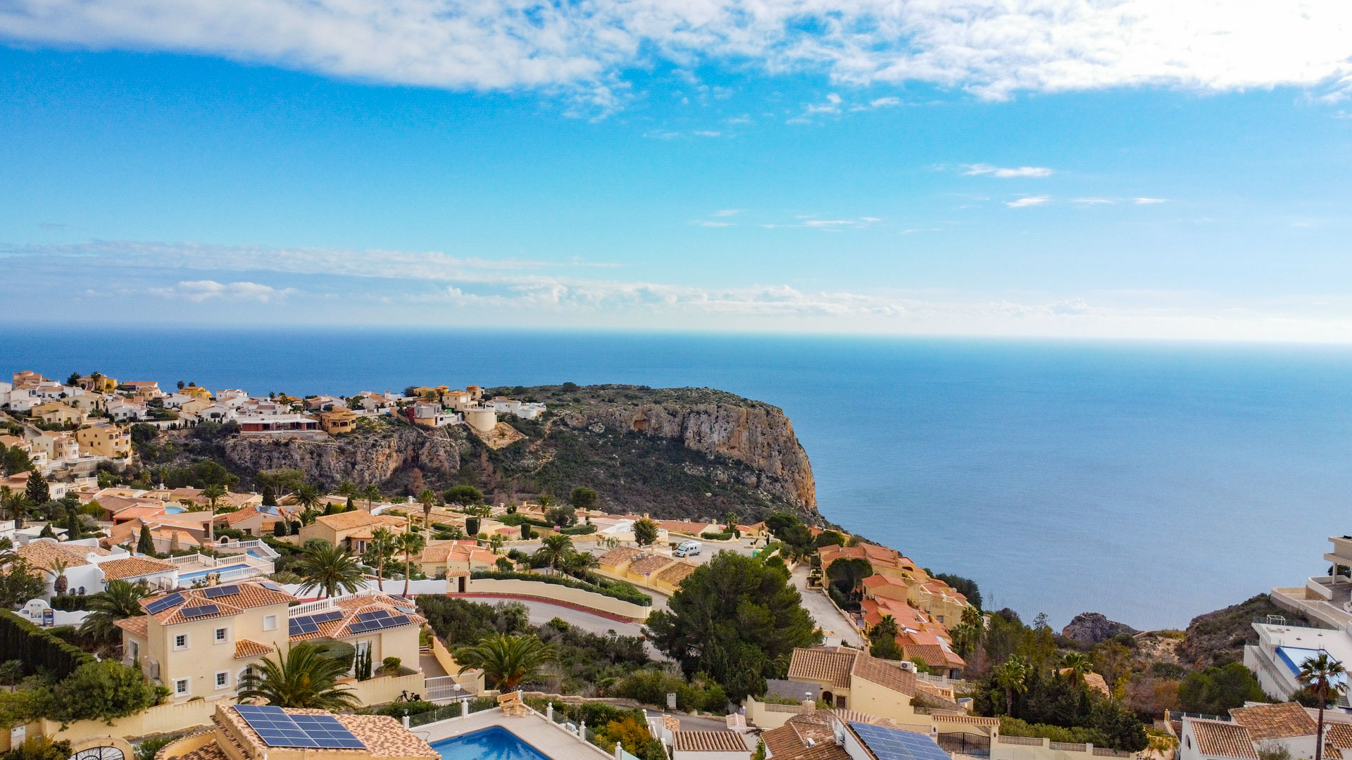 Vue panoramique surélevée de Cumbre del Sol, illustrant l'architecture méditerranéenne, les falaises côtières et l'horizon bleu de la mer Méditerranée.