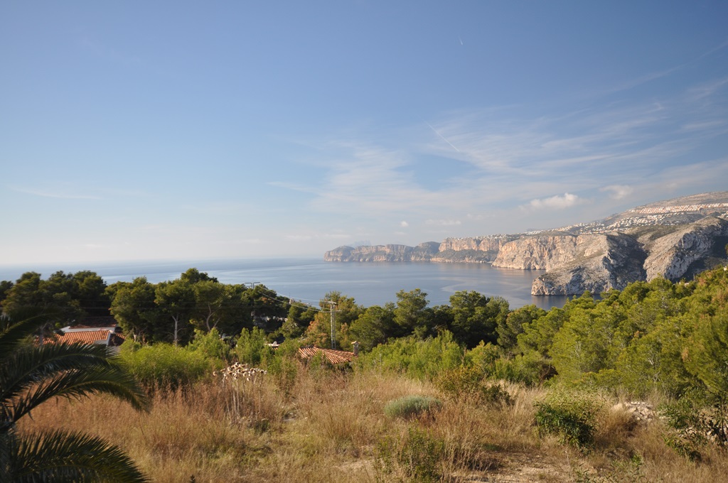Vue panoramique depuis le terrain sur la mer Méditerranée et les falaises côtières, entourée de pins et d'une végétation sauvage.