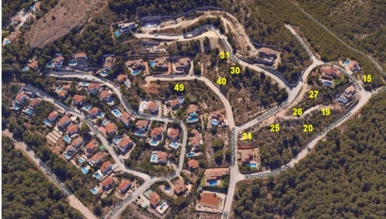 Vue aérienne du lotissement à Jávea, illustrant la disposition des parcelles numérotées au cœur d'une zone boisée avec rues asphaltées et villas.