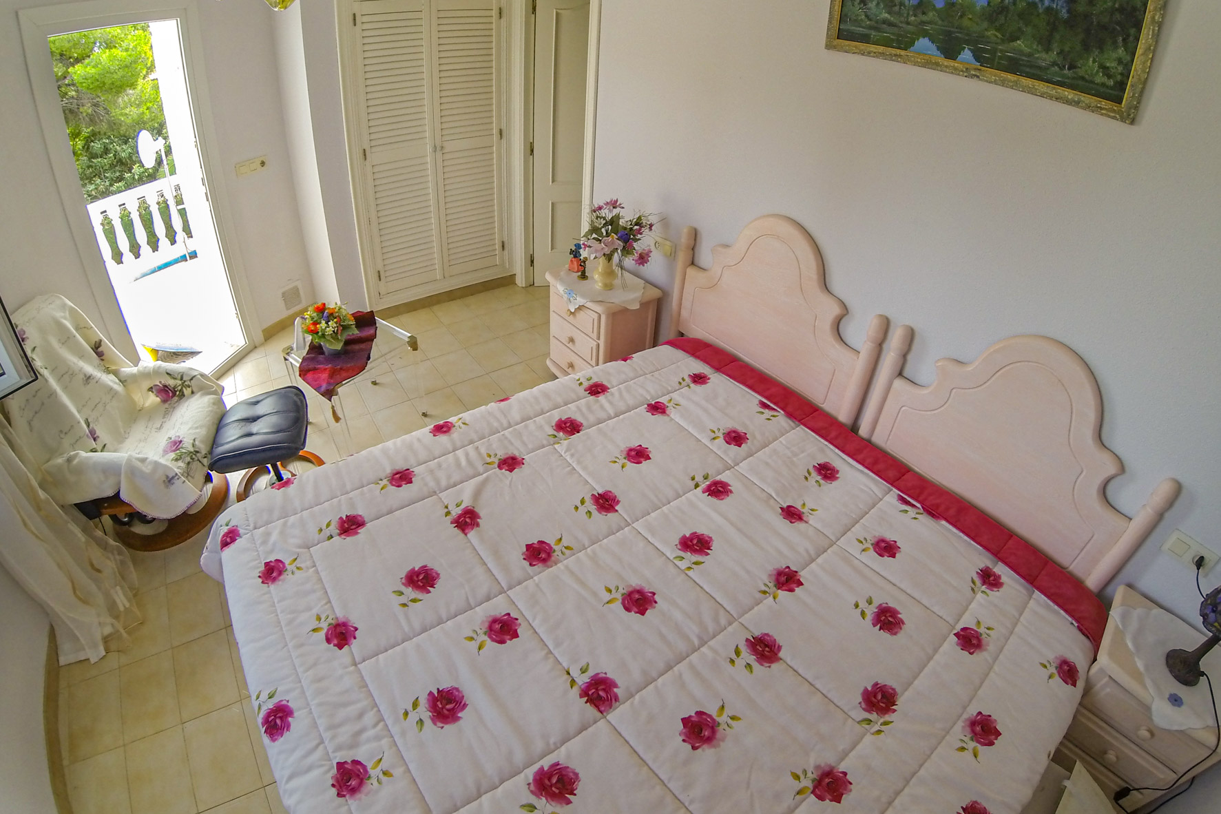 Chambre lumineuse avec lit double, literie florale et accès à la terrasse.