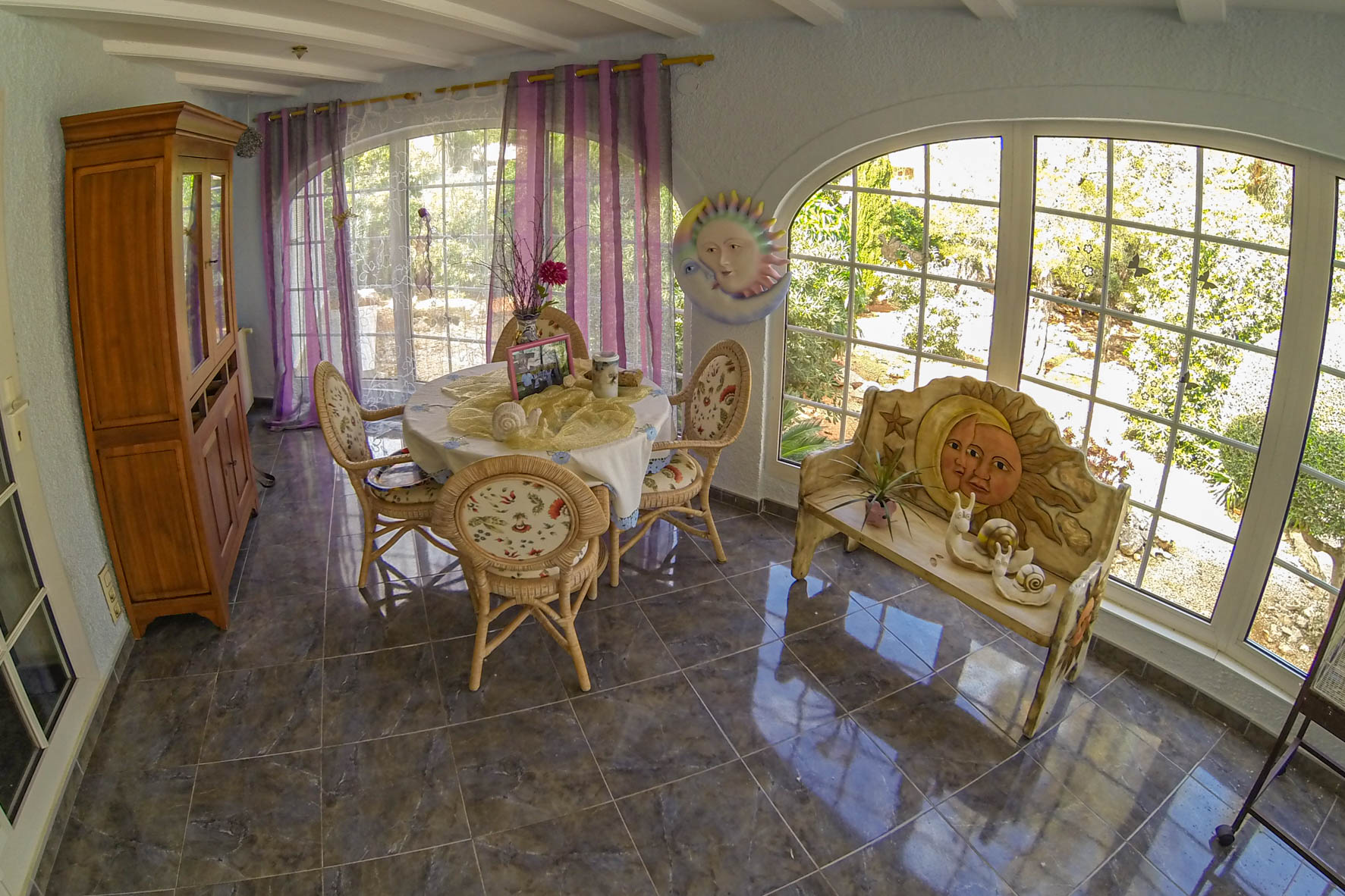 Coin repas lumineux avec table ronde, chaises en osier et décor sur le thème du soleil et de la lune.
