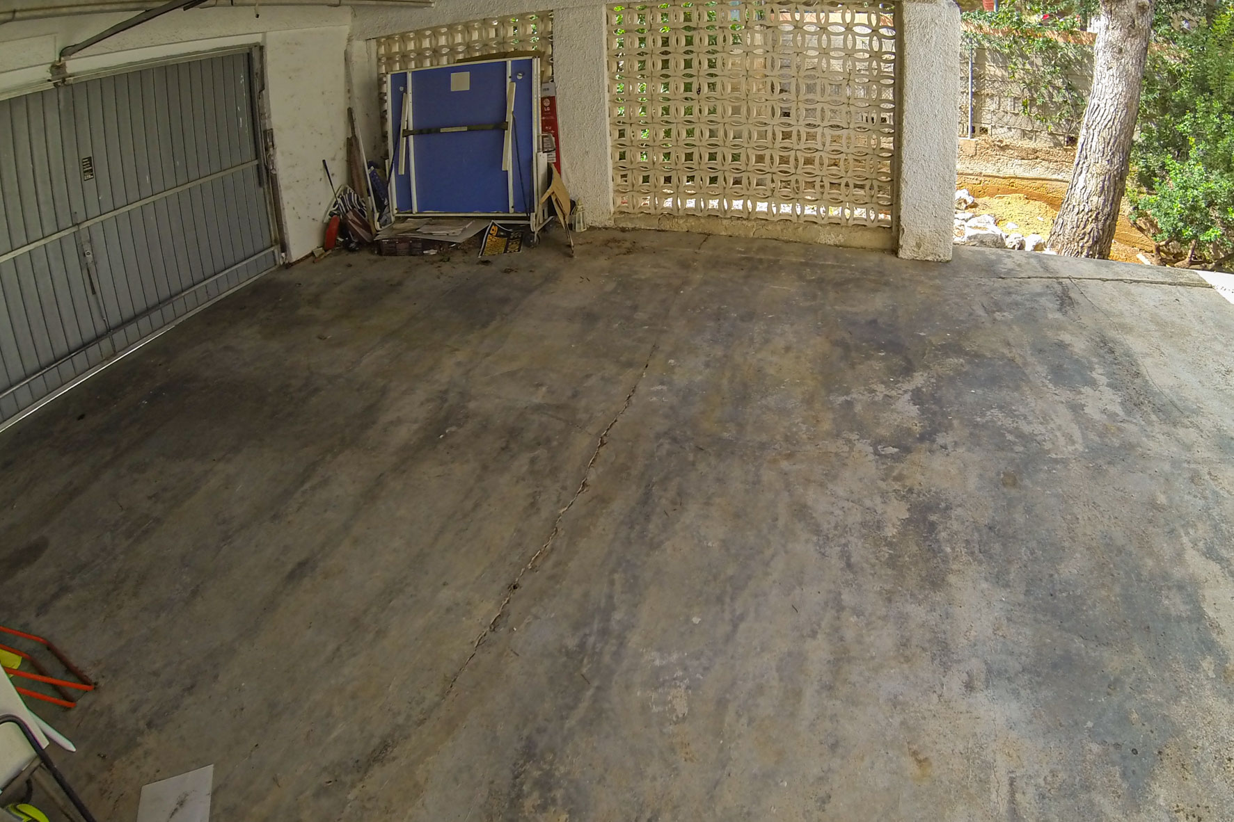 Garage avec porte métallique et mur de blocs décoratifs.