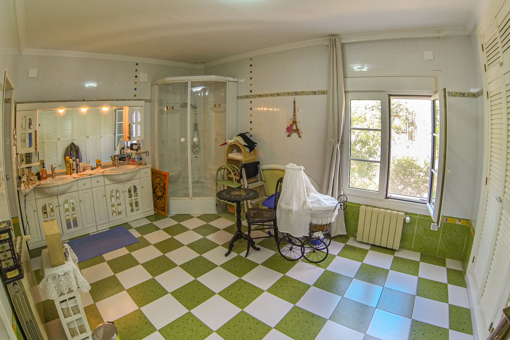 Salle de bain avec carrelage à damier vert et blanc, douche d'angle et meuble-lavabo double avec armoires blanches.